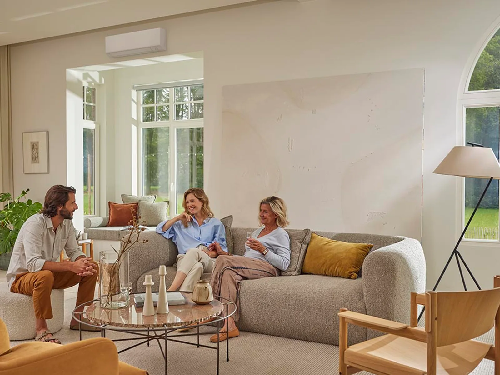 Daikin Perfera FTXM-A wandmodel in een lichte woonkamer met een stel op de bank — strak wit ontwerp